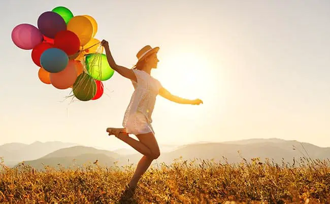 young happy woman with balloons at sunset in summer